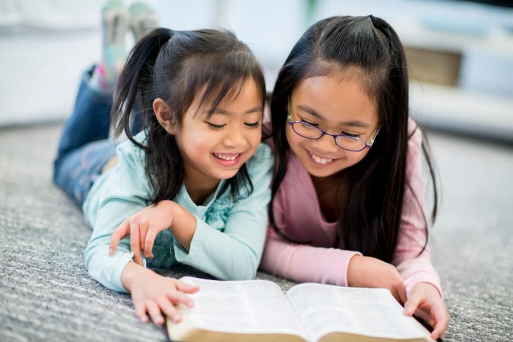 Two young girls reading the bible together
